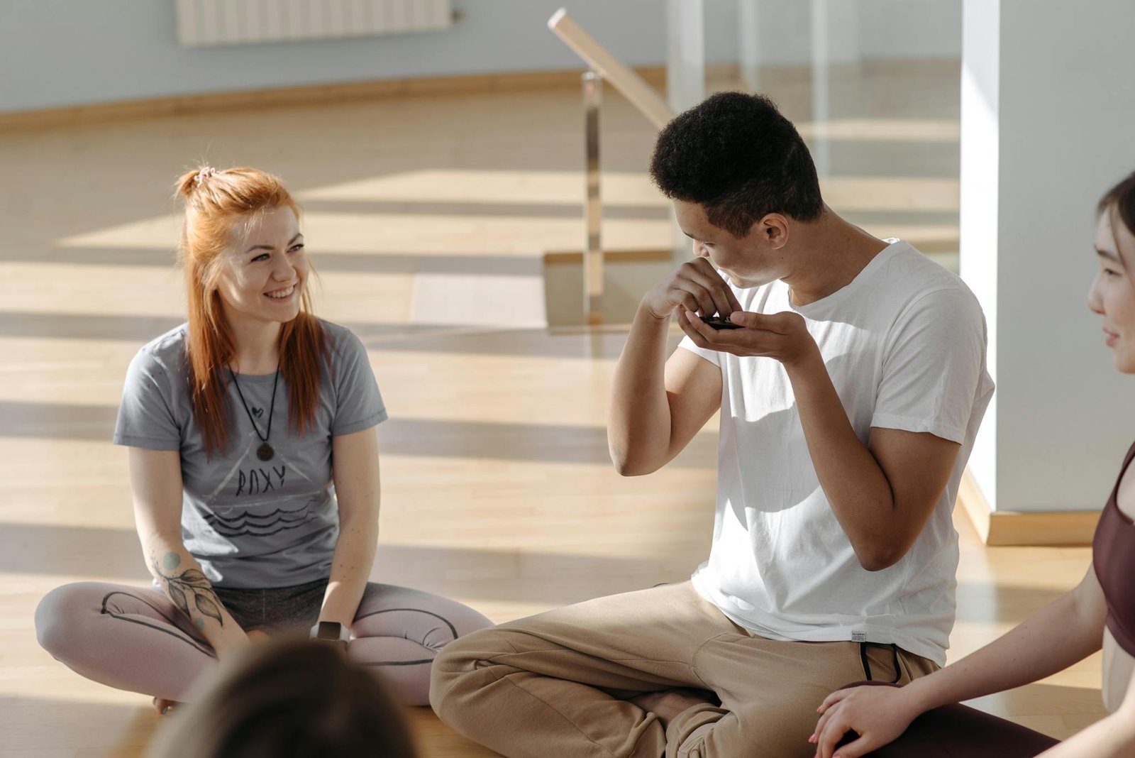 A diverse group of adults enjoying a yoga session in a bright, sunlit room.