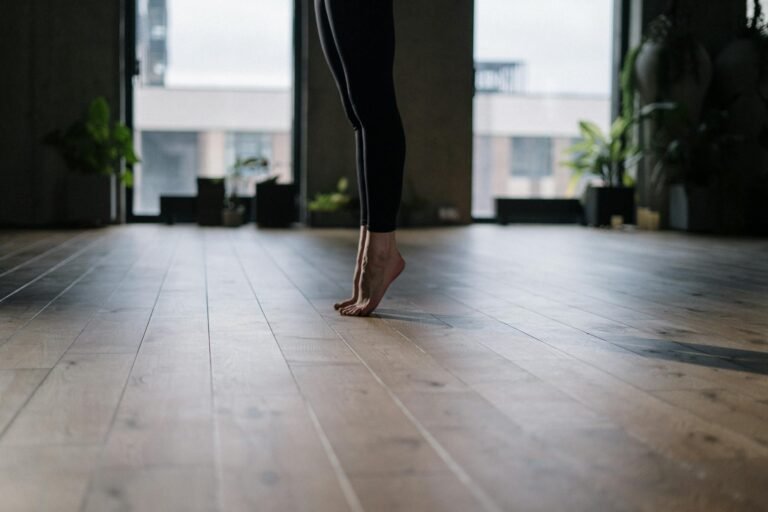 A person practicing a gentle yoga pose indoors, focusing on balance and wellness.