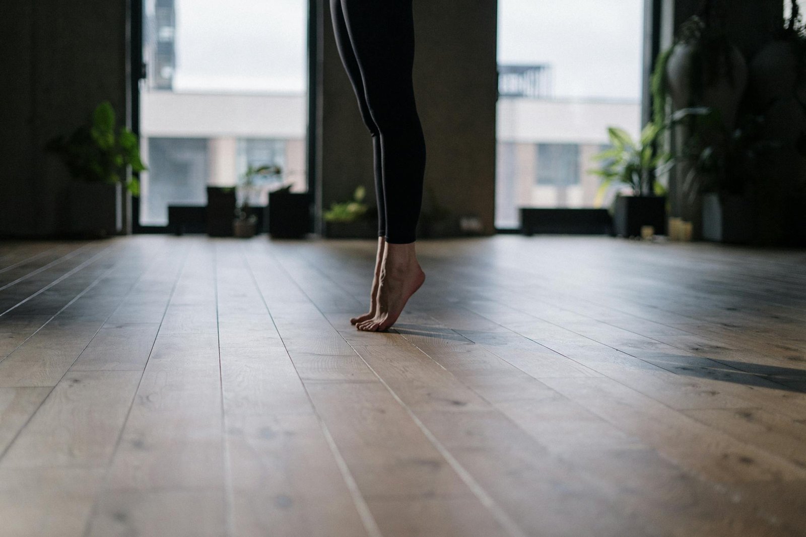 A person practicing a gentle yoga pose indoors, focusing on balance and wellness.